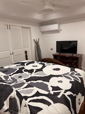 Un dormitorio con cama, cómoda, televisor y equipo de aire acondicionado.