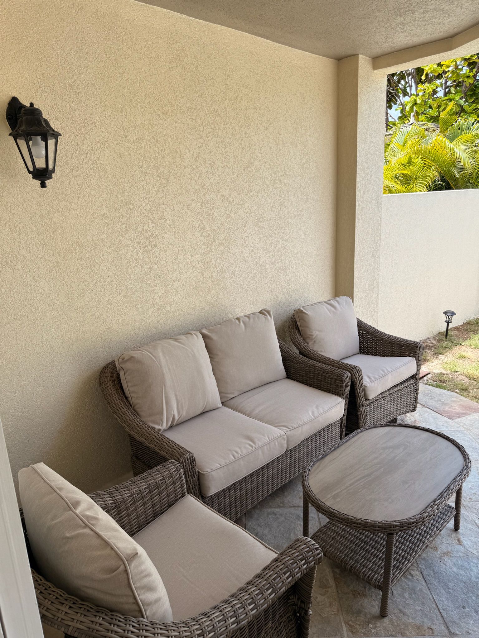 Un'area patio coperta con mobili in vimini, tra cui un divano e un tavolo rotondo.