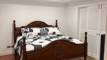 Een slaapkamer met een houten bed, een plafondventilator en een kledingkast met verstelbare deuren.