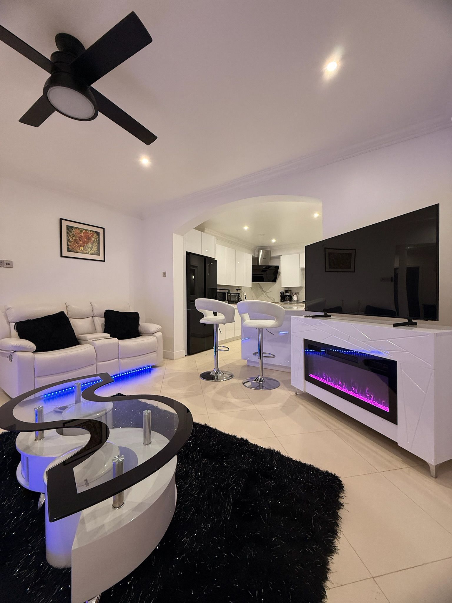 A modern living room with a white sofa, a black and white coffee table, and a ceiling fan.
