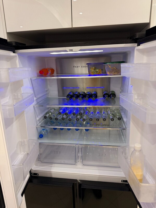A refrigerator with multiple shelves, some containing bottles and containers.
