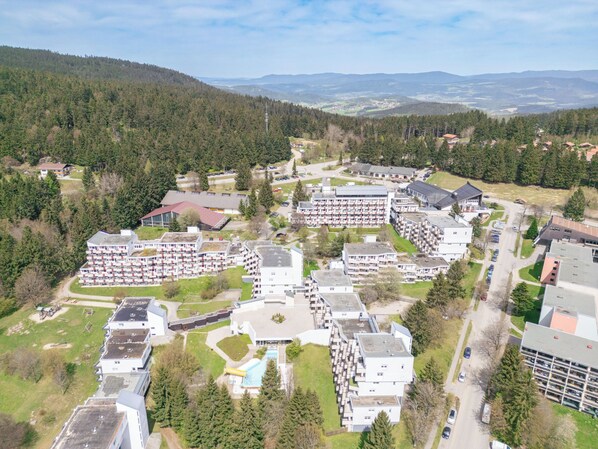 A residential area with multiple apartment buildings, a swimming pool, and a ski lift in the background.