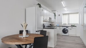 A modern kitchen with white cabinets, a central island, and a built-in washing machine.
