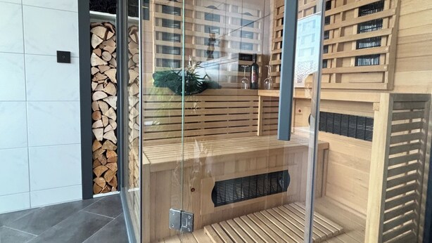 Eine Sauna mit Glasverkleidung, Holzbänken und einem sichtbaren Lüftungssystem.