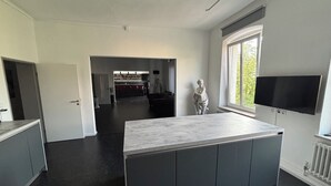 Eine moderne Küche mit dunklen Arbeitsplatten, einer zentralen Kochinsel und einer Bar im Hintergrund.
