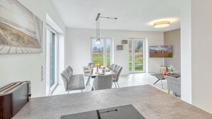 Una cocina moderna con una isla grande, un área de comedor con sillas y un televisor montado en la pared.