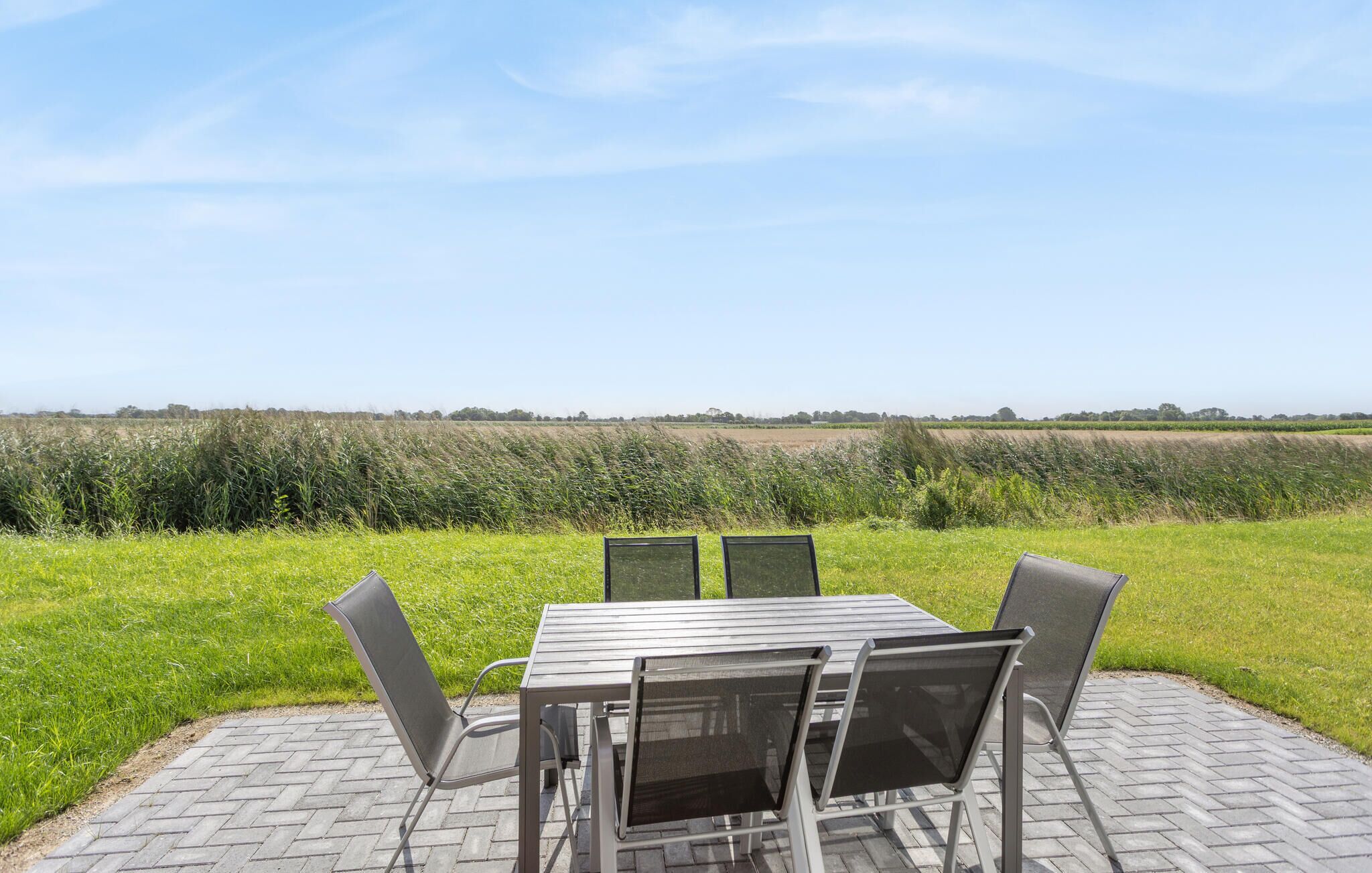 An outdoor patio with a table and chairs, overlooking a field.