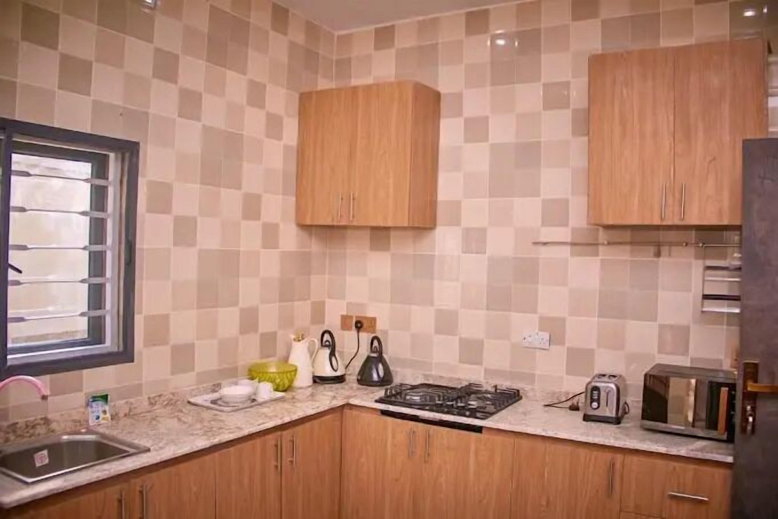 Une cuisine avec des meubles de rangement en bois, une cuisinière à gaz, un évier, un grille-pain et un four à micro-ondes.