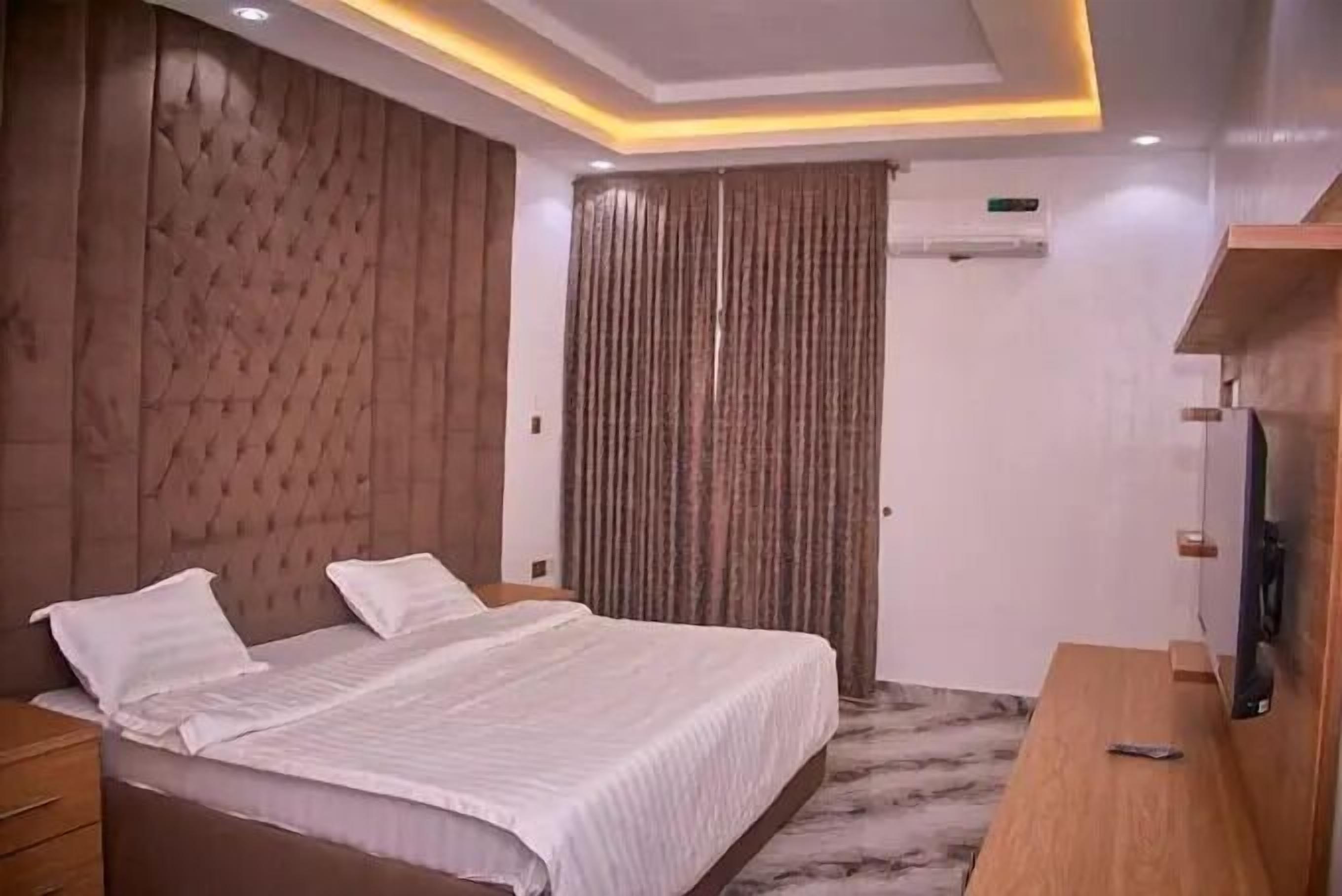 A modern bedroom with a large bed, wooden headboard, and a television on a wooden stand.