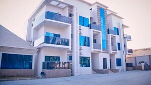 A multi-story building with balconies, large windows, and a central staircase. - Ramlat Apartment  (Kano)