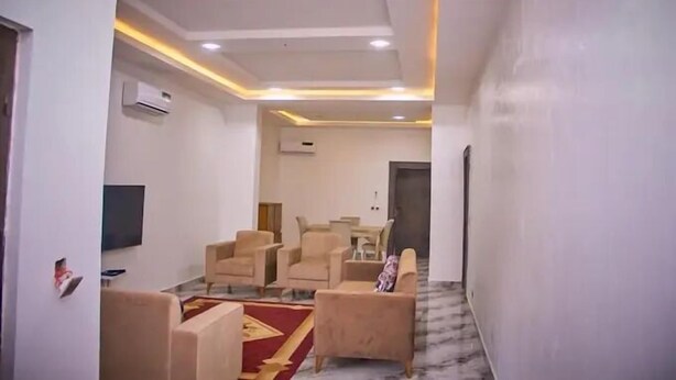 A modern living room with a sofa, armchairs, and a TV. - Ramlat Apartment  (Kano)