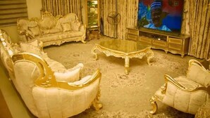 A luxurious living room with ornate furniture, a large television, and a decorative mirror. - Ramlat Apartment  (Kano)