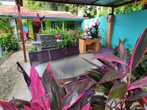 An outdoor patio with a grill, seating area, and potted plants. - Style and Comfort: Tropical Studio Cabina A/C Pool (Herradura)