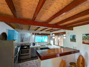 Une cuisine avec un plafond en bois, un réfrigérateur, un four, un évier et une fenêtre.