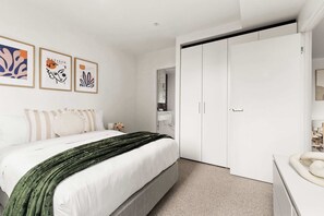 A bedroom with a bed, a wardrobe, and a nightstand.