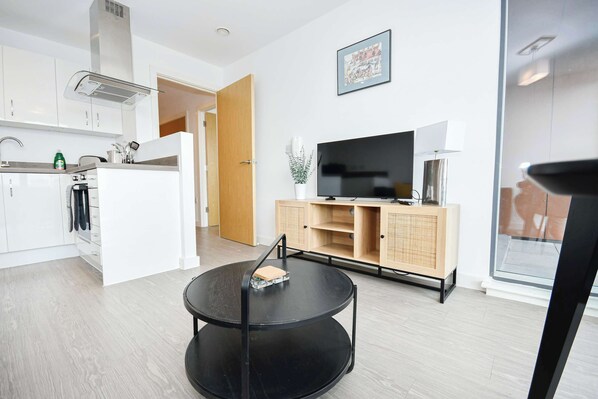 A modern kitchen with white cabinets, a built-in stove, and a dining area with a round black table.