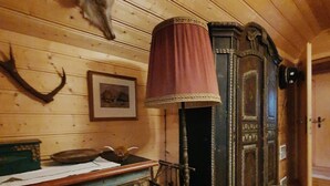 A room with wooden walls, a desk with a lamp, and a door. - Idyllic Cabin With Sauna (Bad Kleinkirchheim)