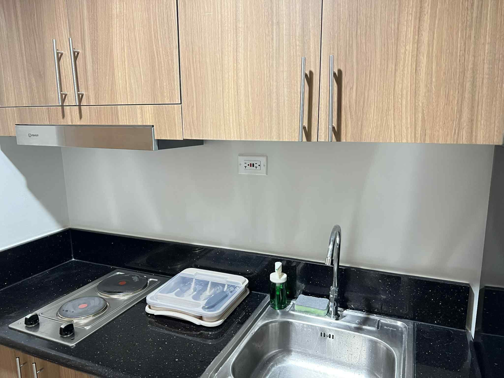 A kitchen with wooden cabinets, a stainless steel sink, and a stove.