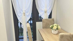 A dining area with a wooden table, four chairs, and a vase of flowers. - CONDO NEXT DOOR PH (Pasay)