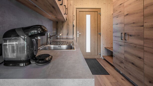 A modern kitchen with a built-in stove, sink, and wooden cabinets. - Cosy apartment for 2 guests with TV and balcony (Kirchberg In Tirol)