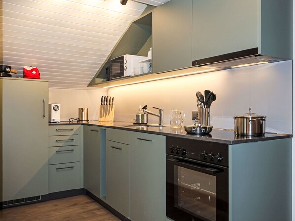 A modern kitchen with a built-in oven, a microwave, and a stainless steel sink.
