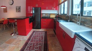 A kitchen with red cabinets, a black refrigerator, a sink, and a ceiling fan. - 2 Bedroom Apartment beautifully decorated in the centre of Sai Kung Town. (New Territories)