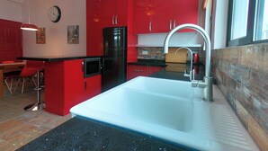 A kitchen with red cabinets, a white sink, and a black refrigerator. - 2 Bedroom Apartment beautifully decorated in the centre of Sai Kung Town. (New Territories)