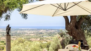 A table with a white umbrella, white chairs, and a view of the countryside. - Beautiful private villa for 4 people with TV and terrace (Badesi)
