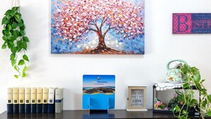 A neatly organized desk with a framed painting of a tree, a travel brochure, and a decorative sign. - Beautiful private villa for 4 people with TV and terrace (Badesi)