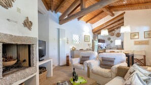 Una sala de estar acogedora con chimenea de piedra, asientos cómodos y una cocina al fondo.