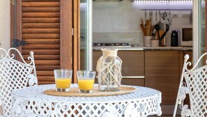 Una mesa redonda con dos vasos de jugo de naranja y un tarro decorativo.
