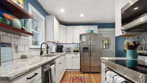 Una cocina moderna con armarios blancos, electrodomésticos de acero inoxidable, encimera de granito y una alfombra estampada roja.