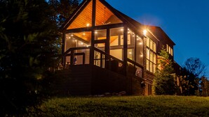 Un grand bâtiment en bois à plusieurs étages, doté d’un balcon imposant et de grandes fenêtres, entouré d’arbres.