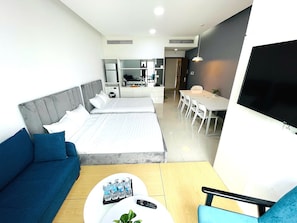 A modern hotel room with a bed, a sofa, a dining table, and a TV. - Diamond Suite Golden King  (Ho Chi Minh City)