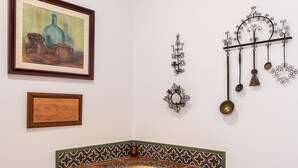 Une cuisine dotée d’un four en briques, d’un pare-feu en carreaux et d’œuvres d’art décoratives, notamment une peinture et des éléments décoratifs en métal fixés au mur.