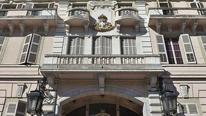 Un edificio classico con balconi decorati, un ingresso centrale con arco ornamentale e uno stemma sopra l'ingresso.