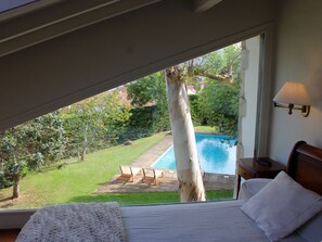 Une chambre avec vue sur une piscine et un jardin.