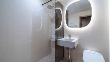 A modern bathroom with a glass-enclosed shower, a white sink, and a toilet.