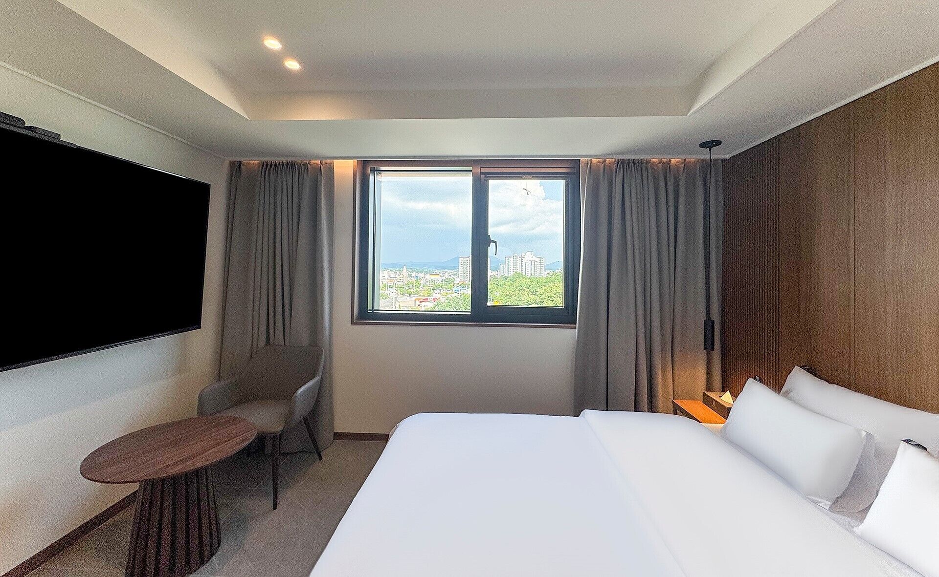 Una habitación de hotel con una cama grande, un escritorio, una silla y un televisor en la pared.