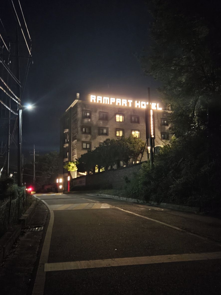 A building with a sign that reads "RAMPART HOTEL" at night.