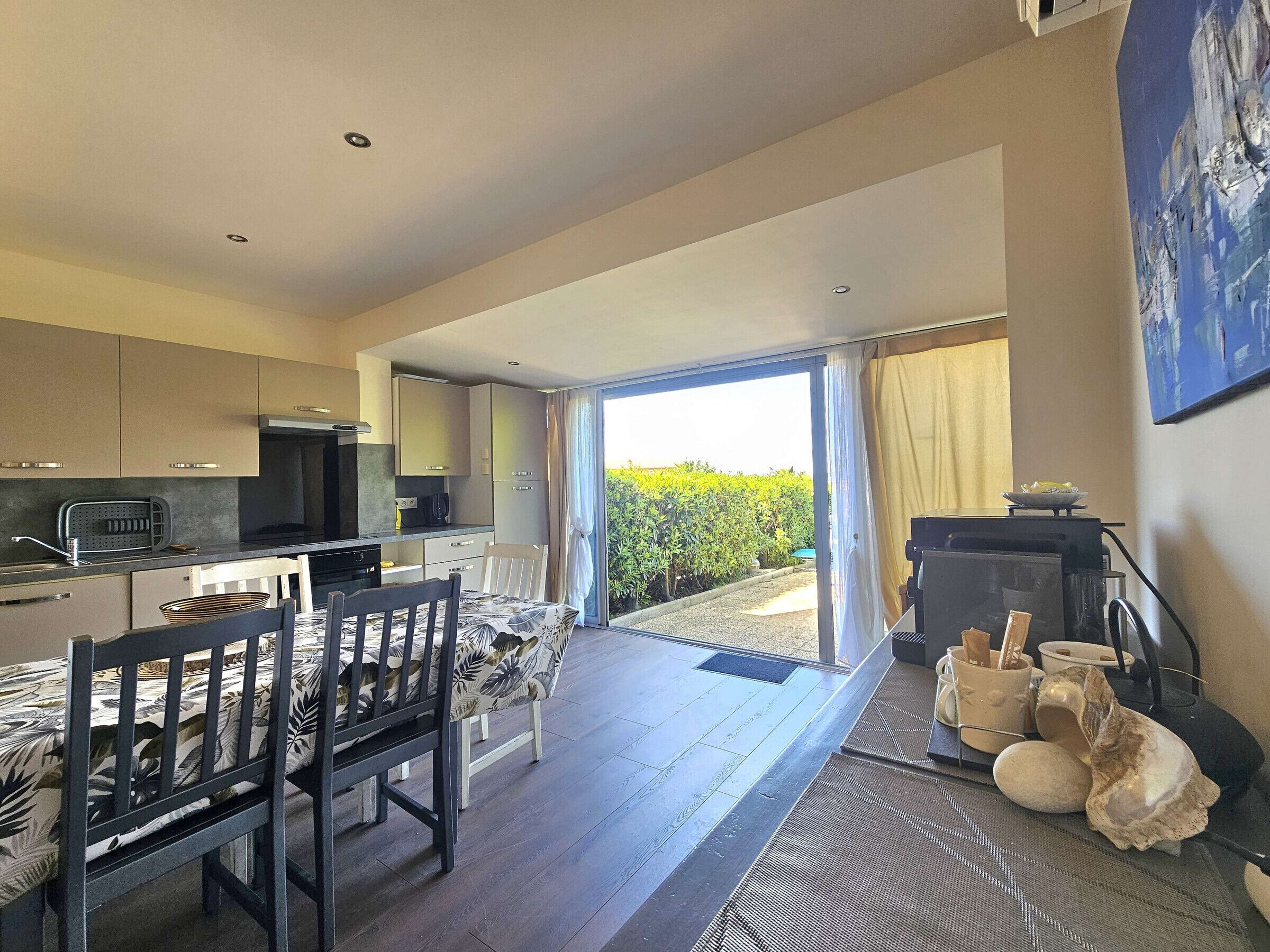 A modern kitchen with a dining area, a grill, and a view of the garden.