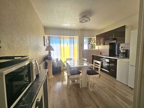 A compact kitchen with a dining area, a refrigerator, a microwave, and a coffee maker. - Comfortable T1 with WIFI included (Balaruc-les-Bains)
