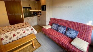 A compact room with a bed, a sofa, and a kitchenette.