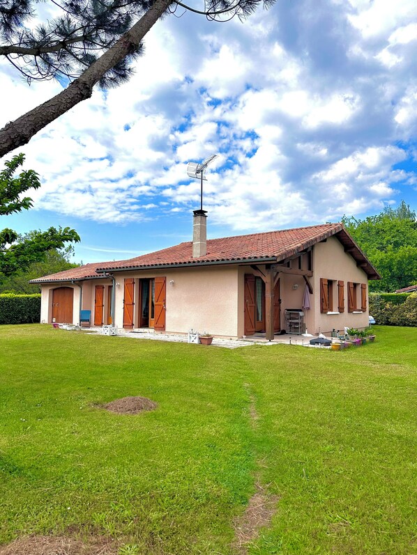 A single-story house with a tiled roof, a chimney, and a small porch area.
