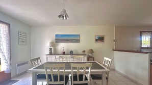 Un coin repas avec une table et des chaises, un luminaire suspendu et un tableau au mur.