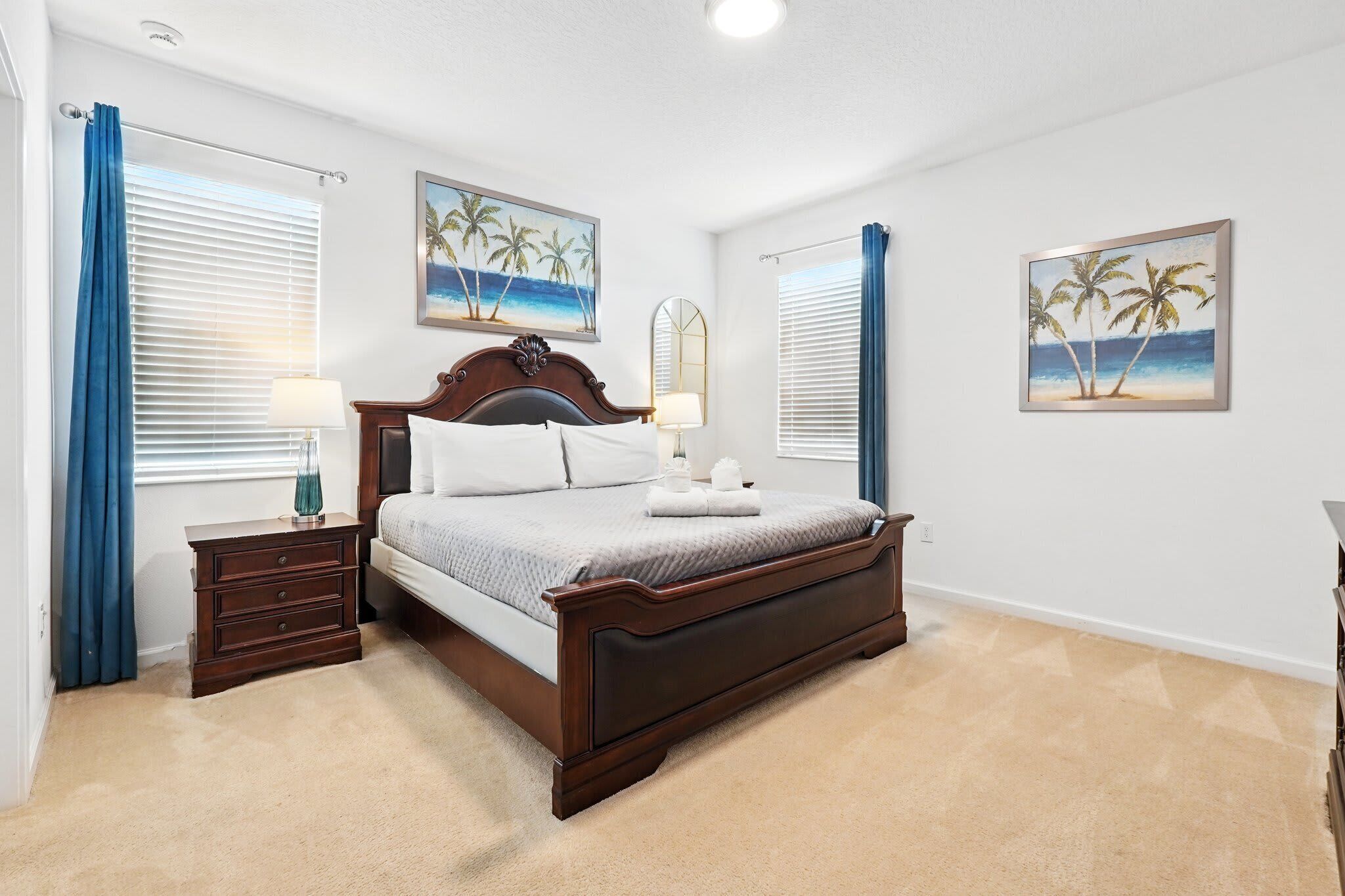 A bedroom with a wooden bed, two bedside tables, a nightstand, and two wall-mounted paintings.