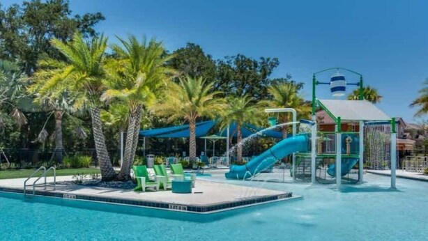 A swimming pool with a slide, lounge chairs, and palm trees. - Lakeview! Big Screen! Resort 6 mi 2 Disney! 2576 (Kissimmee)