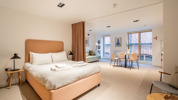 Une chambre d’hôtel moderne dotée d’un grand lit, d’un bureau et d’un coin repas avec des chaises.