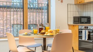 A breakfast table with orange juice, a muffin, and a coffee pot in a modern kitchen with a view of a brick building. - King Street Studios - King Henry IV (York)