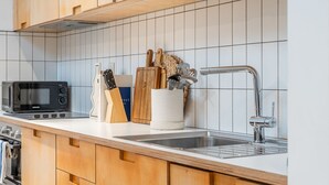 A modern kitchen with wooden cabinets, a microwave, a sink, and various utensils. - King Street Studios - King Henry IV (York)